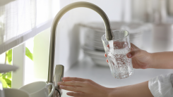 woman filling up a glass of water at the kitchen faucet